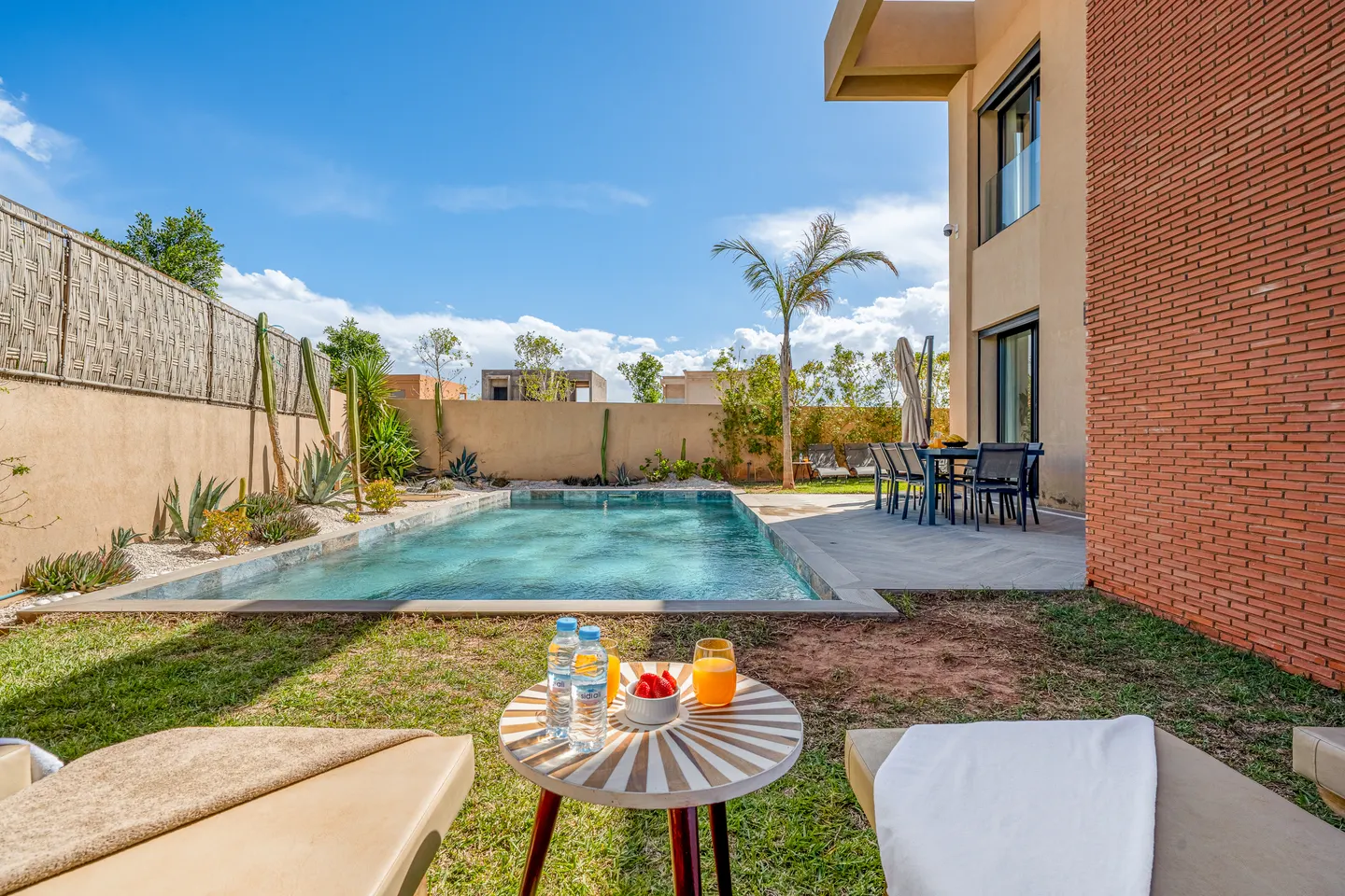 Pool seen from the lawn with a low table set for drinks