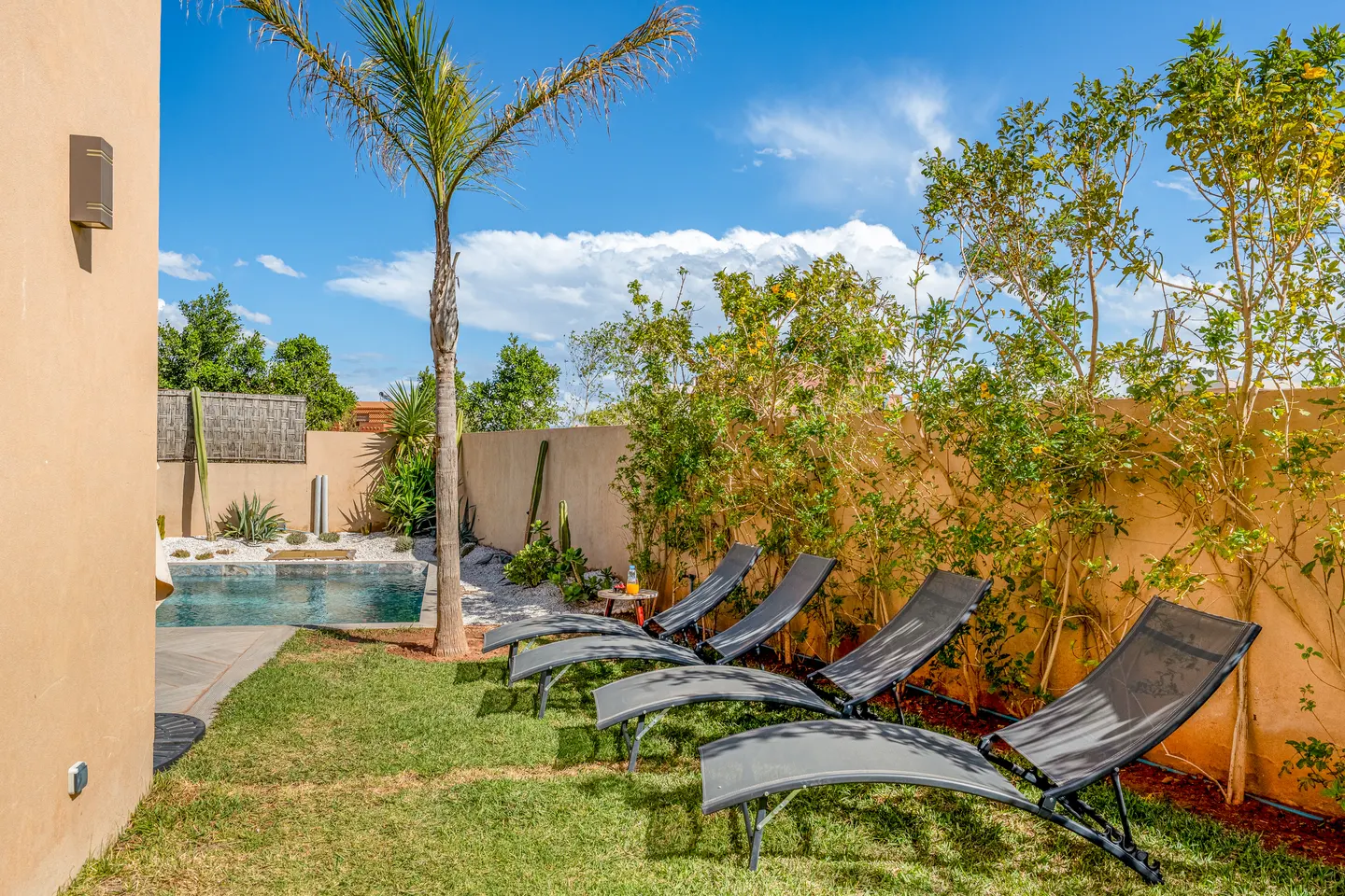 Row of sunbeds on the lawn beside the pool