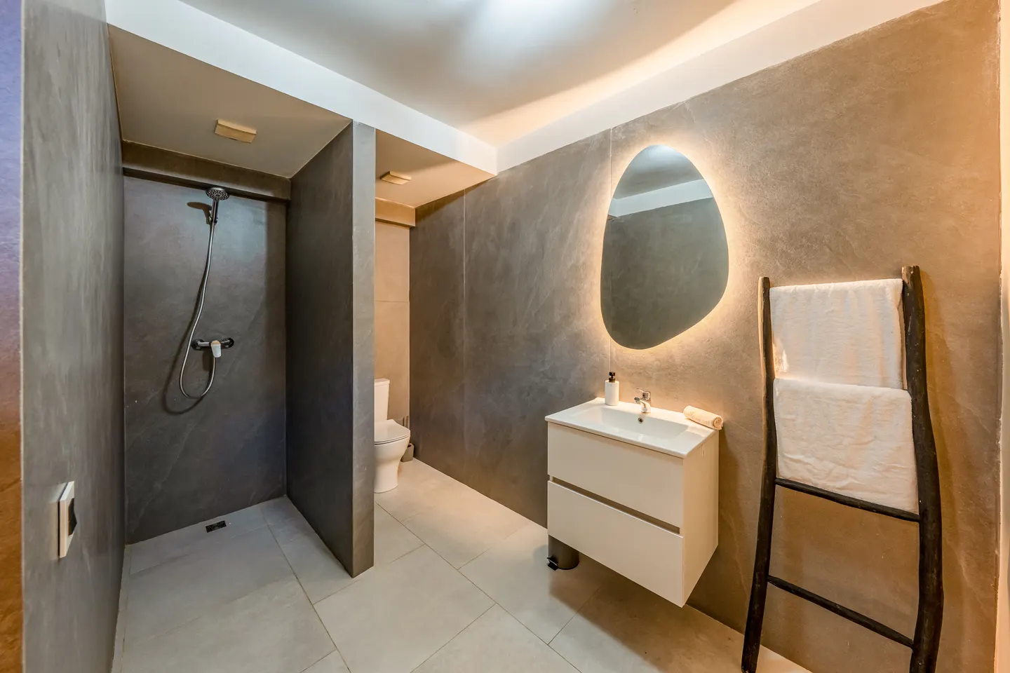 Basement bathroom with dark shower and round mirror