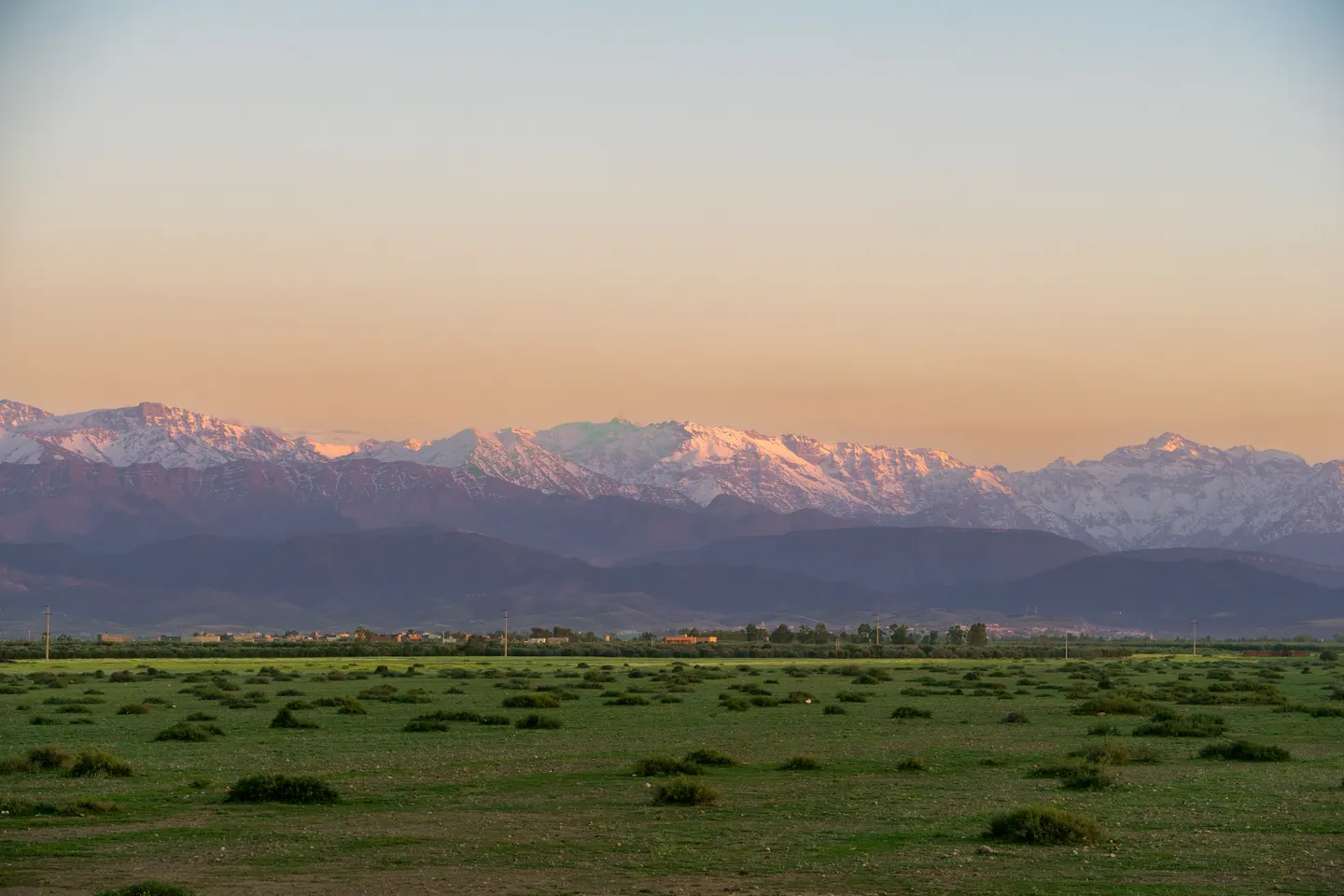 Snow-capped Atlas mountains at sunset beyond the plain